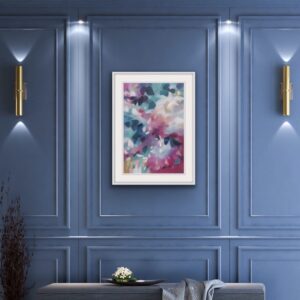 A Softly blended pink and blue abstracted leafy tree canopy painting in a bespoke white frame, set against a rich blue panelled wall with two down lighter wall lights. From the Canopy Series by Irish nature artist Eibhilin Crossan