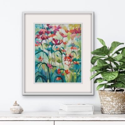 Colourful floral original painting in a white frame of peach flowers growing tall in a garden by Irish nature artist Eibhilin Crossan. A painting set against white wall with a sideboard and a potted plant.