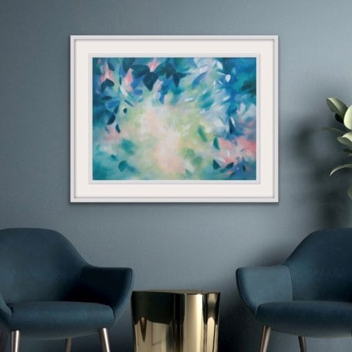 An original painting on canvas in Soft Green and Blue colours with pops of pink, of a leafy tree canopy with a Spring like feel in a bespoke with frame.set against a dark teal wall with two velvet teal armchairs and a gold side table.