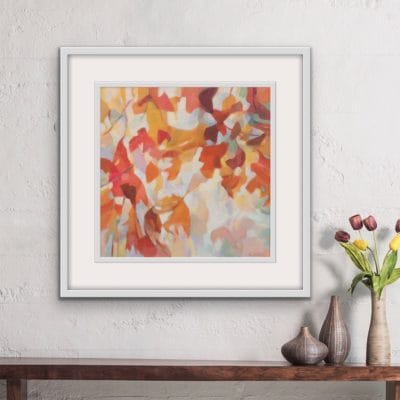An original painting on canvas of a leafy canopy scene in mellow autumnal orange, gold and brown shades, in a bespoke off white frame. Set against a dark green wall over a sideboard with a vase of dried flowers.